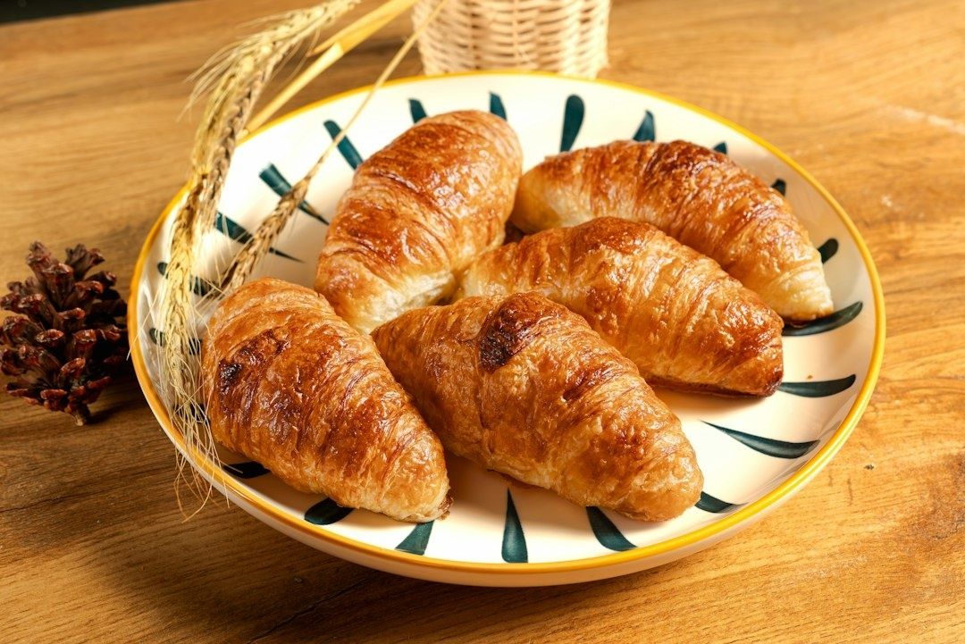 Assiette de croissants dorés dressée sur une table en bois