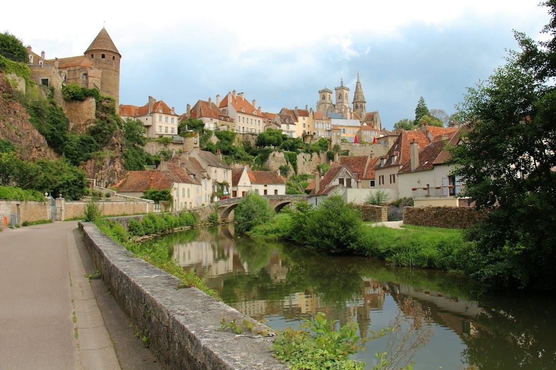Village médiéval aux toits rouges, rivière et église en hauteur
